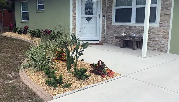 A tidied front garden with new low-maintenance planting and brown river rock