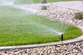 Pop-up sprinklers watering a lawn beside a gravel border