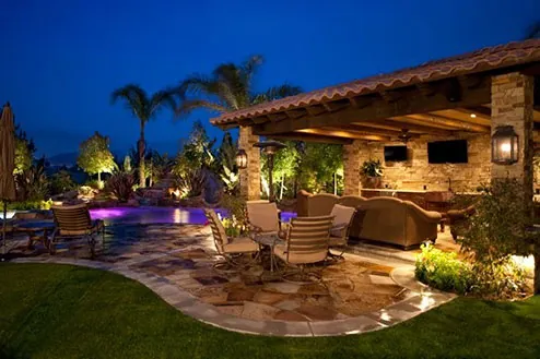 A residential poolside garden lit at dusk by low-voltage landscape lighting